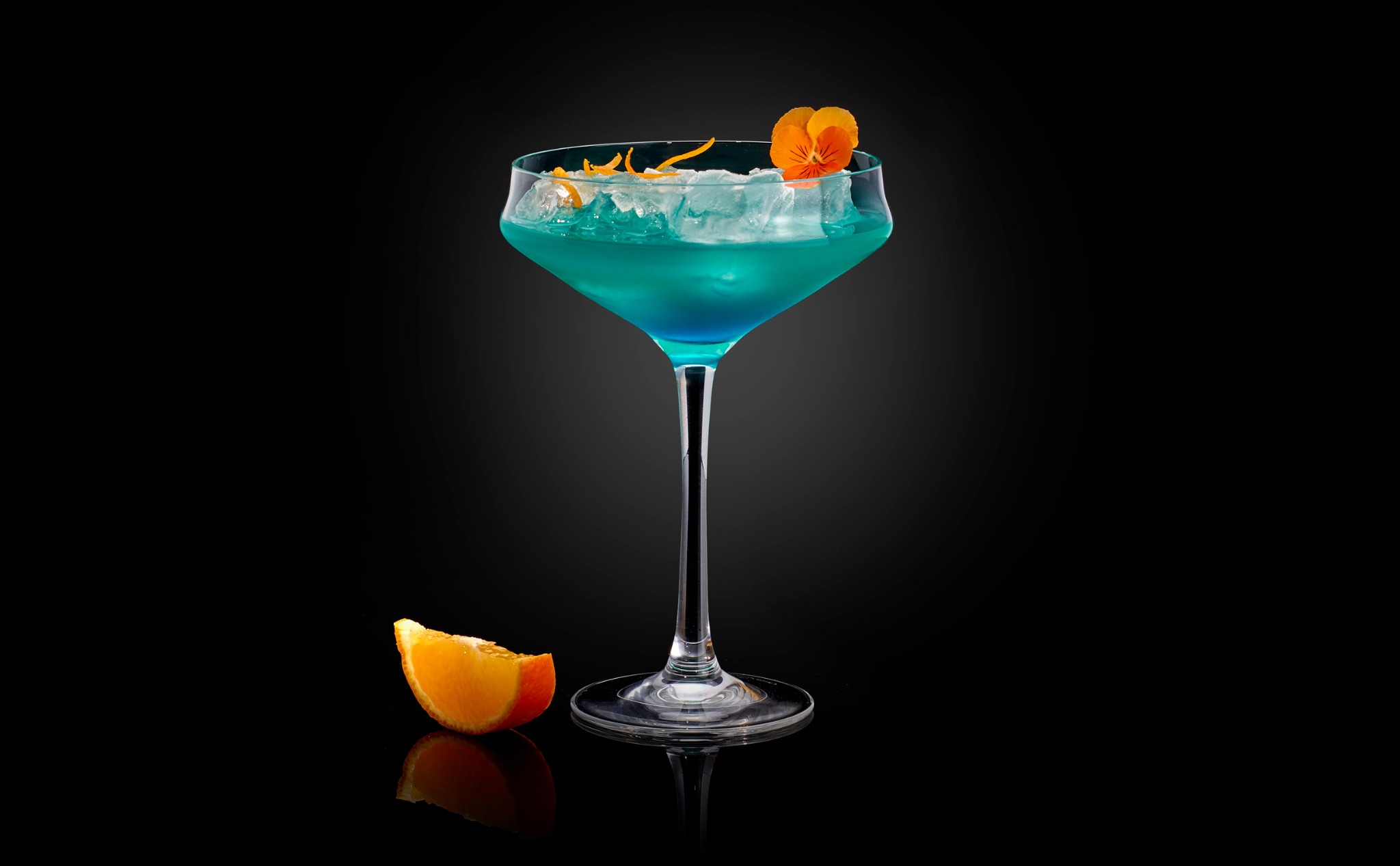 Cocktail bleu et orange photographié en studio sur fond noir.