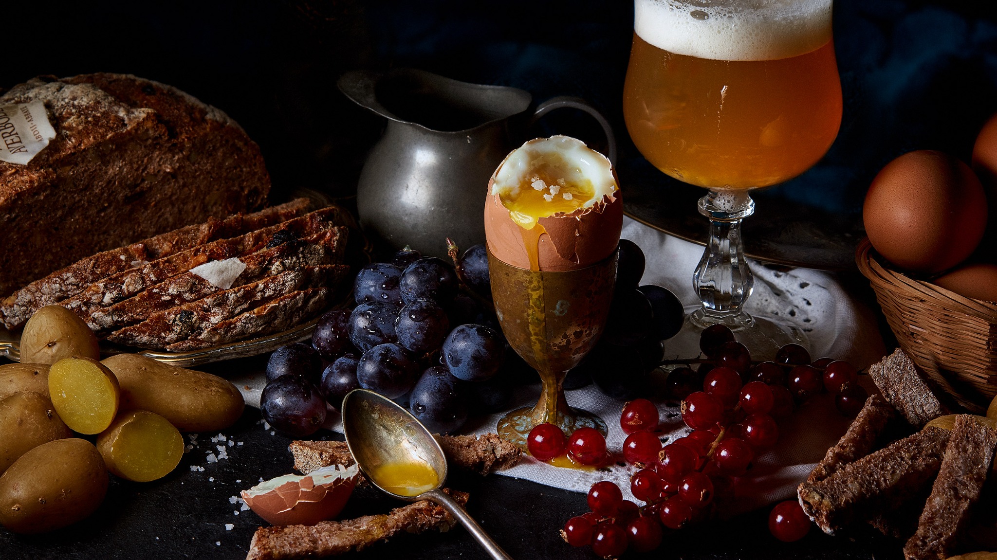 Nature morte culinaire avec œuf à la coque, bière ambrée, pain, pommes de terre et fruits rouges.